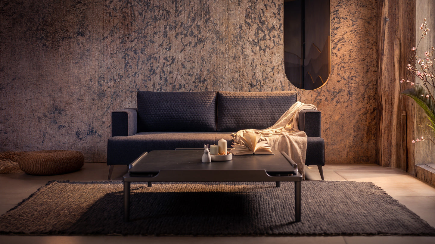 Modern living room with a dark sofa, coffee table, and decorative items against a textured wall | VITTI Living