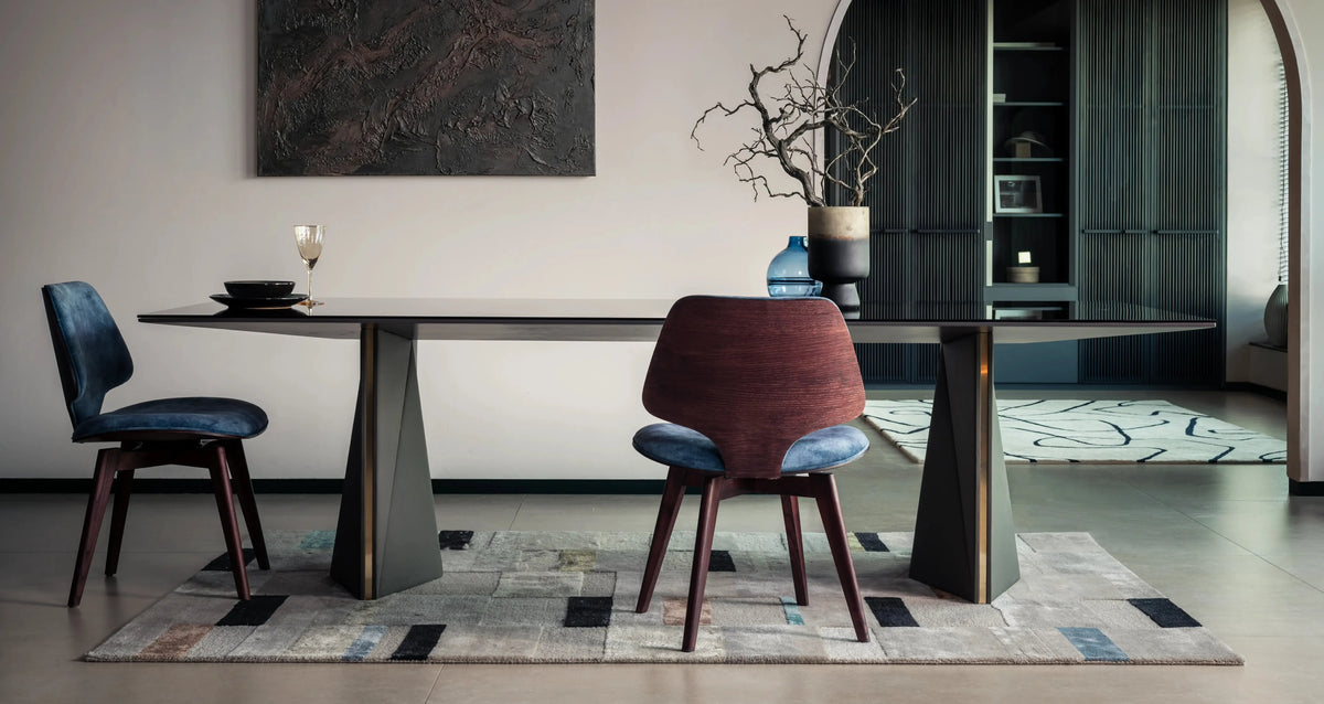Modern dining room with a long table and chairs on a patterned rug.